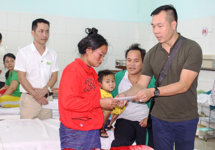 Xạ thủ Hoàng Xuân Vinh tặng quà chị Hồ Thị Xăng-người dân tộc Vân Kiều ở huyện Hướng Hóa có con nhỏ đang được điều trị bệnh tại phòng Cấp cứu của khoa Nhi, Bệnh viện Đa khoa tỉnh Quảng Trị (Ảnh: Lâm Thanh)