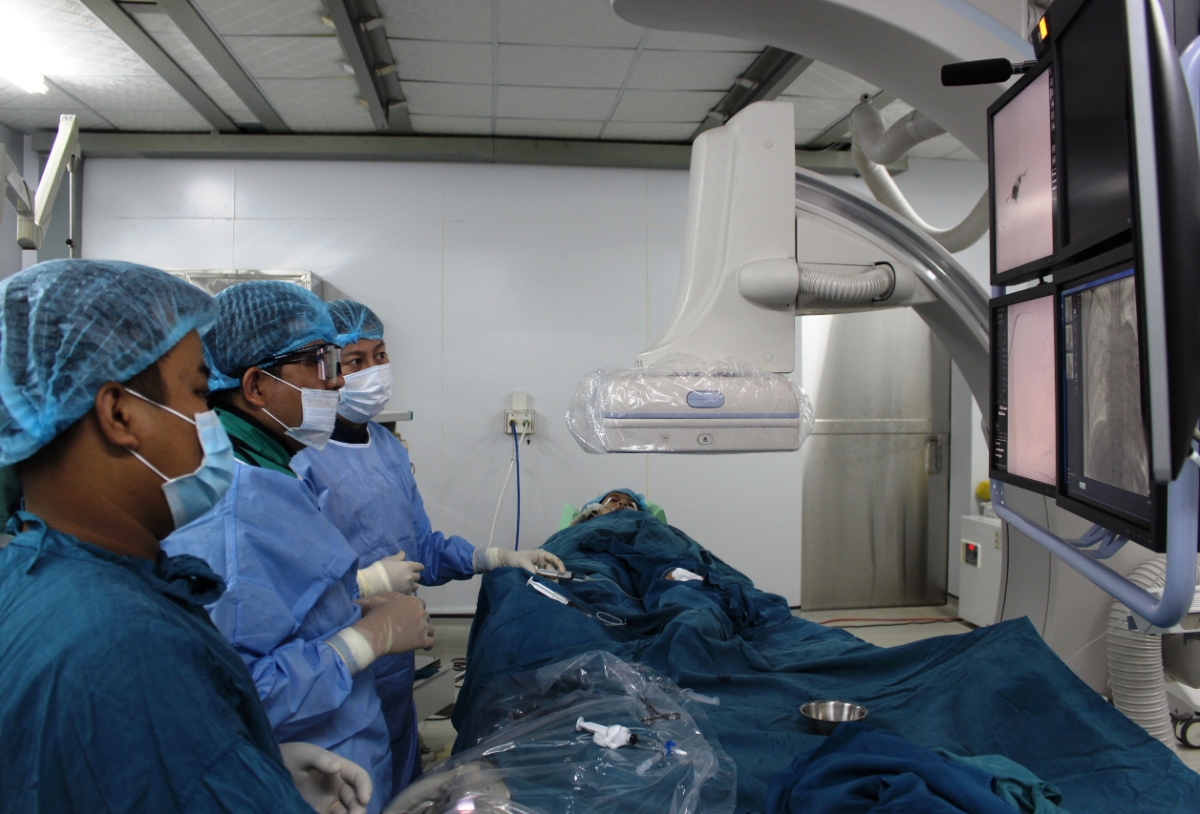 Các bác sỹ tiến hành bơm trực tiếp cồn tuyệt đối vào các ổ dị dạng mạch máu dưới da bên chân trái của Trần Thị Diệu Phương (Ảnh: Bội Nhiên)