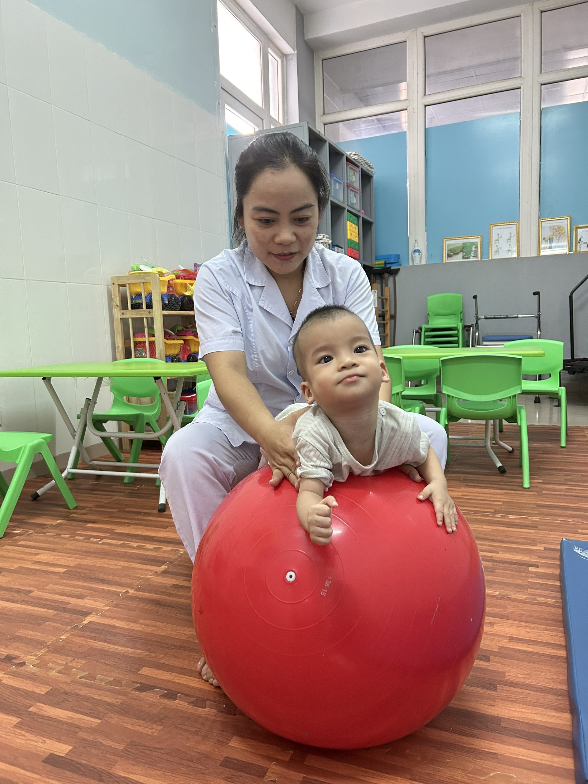 KTV PHCN thực hiện tập mạnh nhóm cơ lưng với bóng cho bệnh nhi